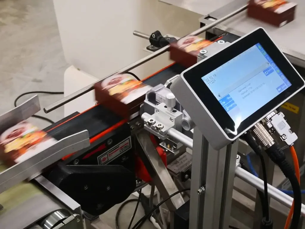 Mindesthaltbarkeitsdatum Codierung auf einer Faltschachtel am Förderband